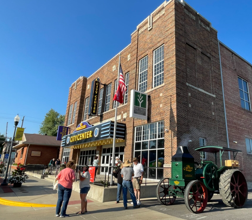 Rushville City Center on a sunny day, with visitors at the entrance and a vintage tractor parked outside